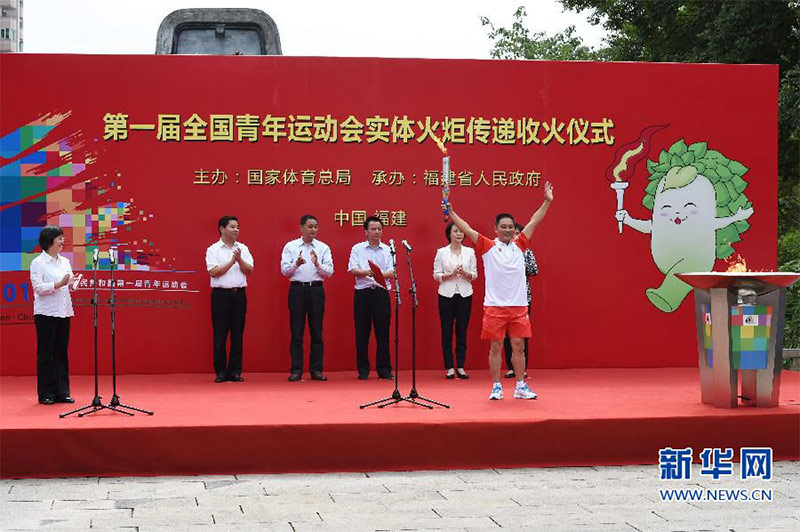 最后一棒火炬手、勞模代表鄭貞良(前)點燃聖火盆后向觀眾致意。